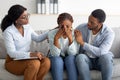 Young black woman crying at therapist& x27;s office, affectionate husband supporting her with professional psychologist Royalty Free Stock Photo