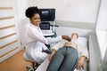 Young black woman doctor sonographer using ultrasound machine at work, holding ultrasound scanner in hand while examine Royalty Free Stock Photo