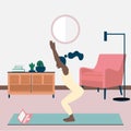 A young black woman does yoga online in her apartment. The girl standing in the chair pose Utkatasana. Home practice of