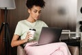 Young black woman drinking coffee while working with laptop Royalty Free Stock Photo
