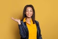 Young black woman with empty open hand for advertising marketing or product placement standing on colorful yellow background