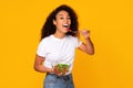 Young black woman enjoying fresh green salad over yellow background Royalty Free Stock Photo