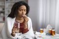 Black woman feeling unwell at home, taking pill with glass of water Royalty Free Stock Photo