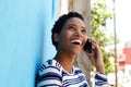 Young black woman leaning against wall and talking on mobile phone Royalty Free Stock Photo