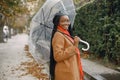 Young black woman in a coat standing under a transparent umbrella outside Royalty Free Stock Photo