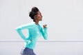 Young black woman running outside with earphones