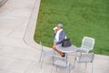 A young black woman is sitting on a chair by a green lawn, drinking coffee, taking a break Royalty Free Stock Photo