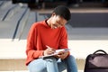 Young black woman sitting outside writing in book Royalty Free Stock Photo