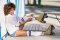 Young black woman sitting on wooden floor puts on skates. Royalty Free Stock Photo