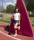 Young black woman,strong look at side.Street style.Sport style.She poses with a basketball in the field.Novi Sad.