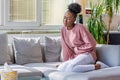 Young black woman suffering from stomachache on sofa at home. Woman sitting on bed and having stomach ache. Young woman suffering Royalty Free Stock Photo