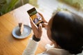 Young black woman at table makes photo of sweets and coffee on smartphone screen in cafe, top view, cropped