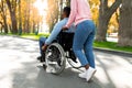 Young black woman taking her paraplegic boyfriend in wheelchair for walk at urban park in autumn Royalty Free Stock Photo