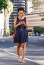 Young black woman walking in city with smart phone and purse Royalty Free Stock Photo