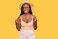 Young black woman wearing summer hat excited for success with arms raised and eyes closed celebrating victory smiling Royalty Free Stock Photo