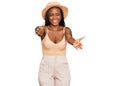 Young black woman wearing summer hat looking at the camera smiling with open arms for hug Royalty Free Stock Photo