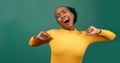 Young Black woman yawns and stretches, green background studio video