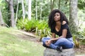 A young black woman between 20 and 30 years old sitting reading a book alone, in a park Royalty Free Stock Photo