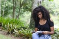 A young black woman between 20 and 30 years old sitting reading a book alone, in a park Royalty Free Stock Photo