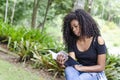 A young black woman between 20 and 30 years old sitting reading a book alone, in a park Royalty Free Stock Photo