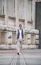 Young blind man with white cane walking across the street in city.