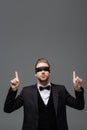 young, blindfolded businessman pointing up with