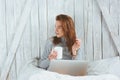 Young blogger or business woman working at home with social media, drinking coffee in early morning in bed Royalty Free Stock Photo