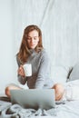 Young blogger or business woman working at home with social media, drinking coffee in early morning in bed Royalty Free Stock Photo