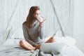 Young blogger or business woman working at home with social media, drinking coffee in early morning in bed Royalty Free Stock Photo