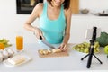 Young blogger preparing fruit salad, cutting banana and recording new video recipe for her food blog Royalty Free Stock Photo