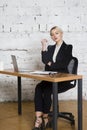 Young blond beauty businesswoman sitting at a office table with laptop, notebook and glasses in suit. Business concept.