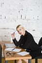 Young blond beauty businesswoman sitting at a office table with laptop, notebook and glasses in suit. Business concept.