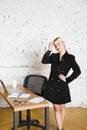 Young blond beauty businesswoman sitting at a office table with laptop, notebook and glasses in suit. Business concept.