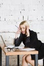 Young blond beauty businesswoman sitting at a office table with laptop, notebook and glasses in suit. Business concept. Royalty Free Stock Photo