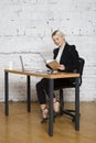 Young blond beauty businesswoman sitting at a office table with laptop, notebook and glasses in suit. Business concept.