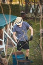 Young blond boy with a hat is chopping branches for later burning. Processing cut branches from fruit trees in orchards. Cutting