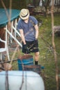 Young blond boy with a hat is chopping branches for later burning. Processing cut branches from fruit trees in orchards. Cutting