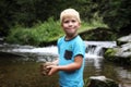 Young blond boy holding stone by the river
