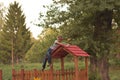 Young blond boy leaning on the red roof top playground house