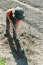 Young blond boy plowing and raking and preparing his vegetable plot in a garden Royalty Free Stock Photo