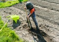 Young blond boy plowing and raking and preparing his vegetable plot in a garden Royalty Free Stock Photo