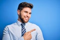 Young blond businessman with beard and blue eyes wearing elegant shirt and tie standing cheerful with a smile of face pointing Royalty Free Stock Photo