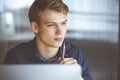 Young blond businessman thinking about strategy at his working place with computer. Startup business means working hard Royalty Free Stock Photo