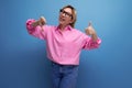 young blond caucasian woman model with ponytail hairstyle in a stylish look consisting of a pink blouse and jeans shows Royalty Free Stock Photo