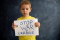 Young blond child, holding sign in support to peace, no war wanted, kid wishing peaceful life