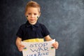 Young blond child, holding sign in support to peace, no war wanted, kid wishing peaceful life