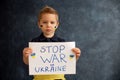 Young blond child, holding sign in support to peace, no war wanted, kid wishing peaceful life