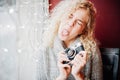 Young blond curly girl with film camera aping in cafe Royalty Free Stock Photo