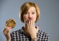 Young blond cute and friendly caucasian woman in casual clothes holding big delicious chocolate cookie Royalty Free Stock Photo