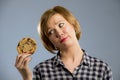 Young blond cute and friendly caucasian woman in casual clothes holding big delicious chocolate cookie Royalty Free Stock Photo